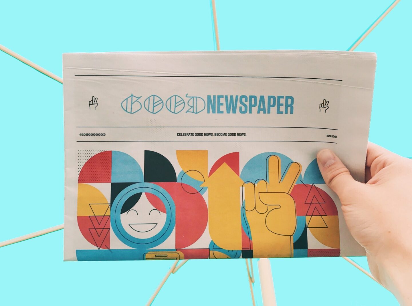 Good Newspaper, text on a newspaper with a cartoon, abstract yellow and red illustration, held up by a hand against a turquoise blue background. 