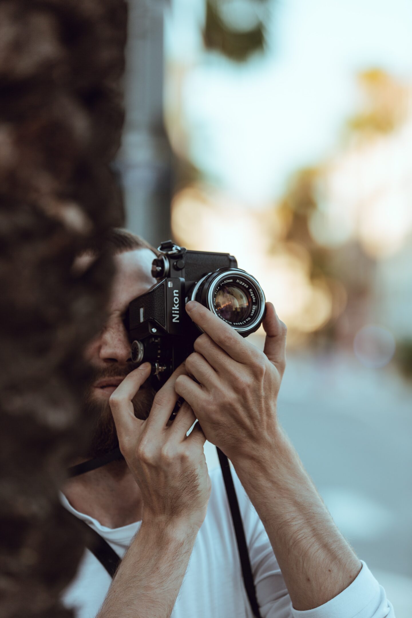 Person holding up a camera, their hand is seen holding the camera, but it covers their face.